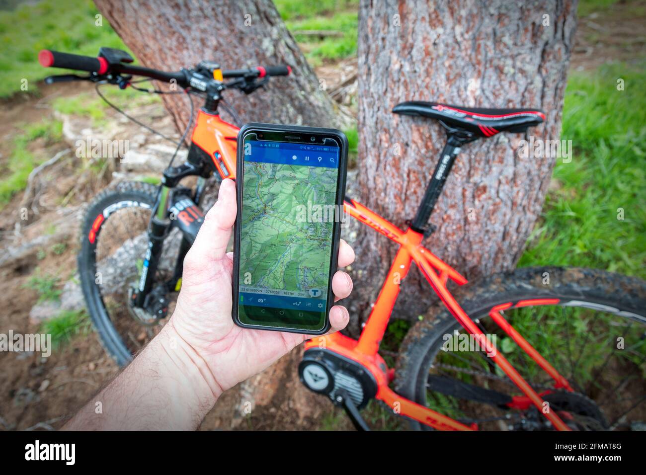 ciclista con e-bike consulta la mappa di un app su smartphone durante un'escursione attraverso sentieri sterrati nelle dolomiti, belluno, veneto, italia Foto Stock