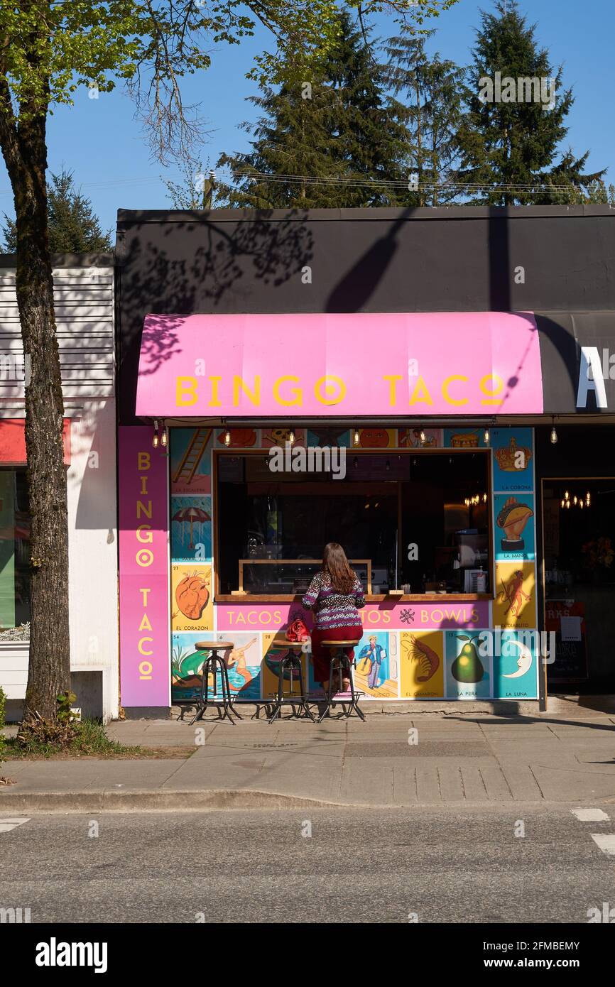 Donna seduta su uno sgabello al bancone dello stand taco messicano su Main Street, Vancouver, British Columbia, Canada Foto Stock