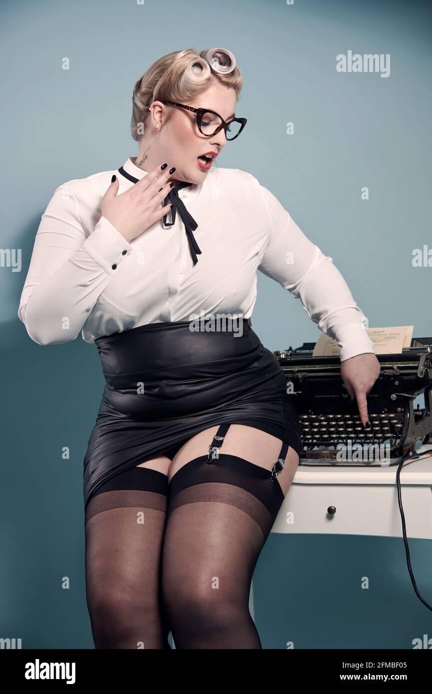 Biondo pin-up nel look segretaria con macchina da scrivere Foto Stock Biondo pin-up nel look segretaria con macchina da scrivere Foto Stock