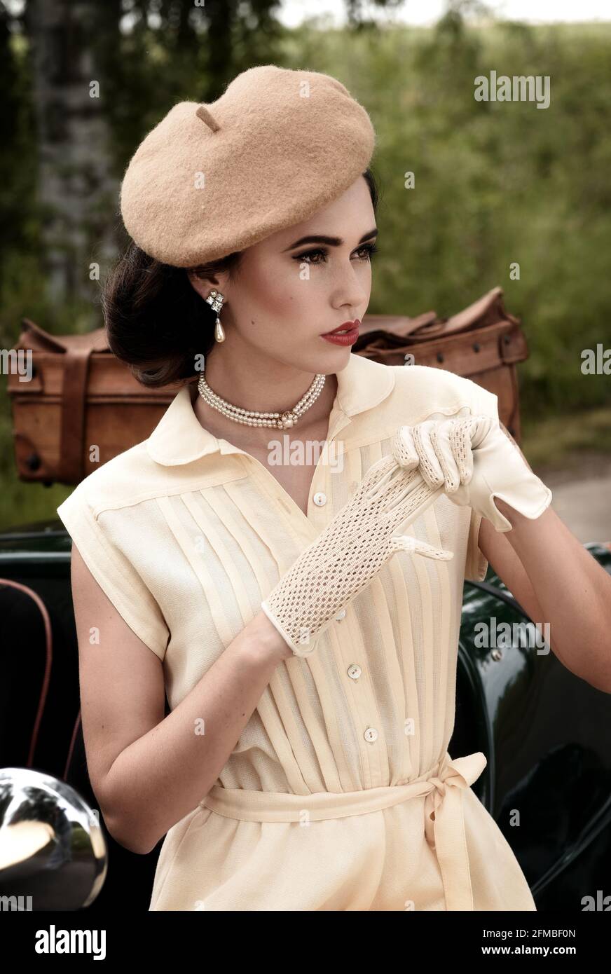 Giovane donna in stile anni '40 con auto d'epoca in British Racing Verde Foto Stock