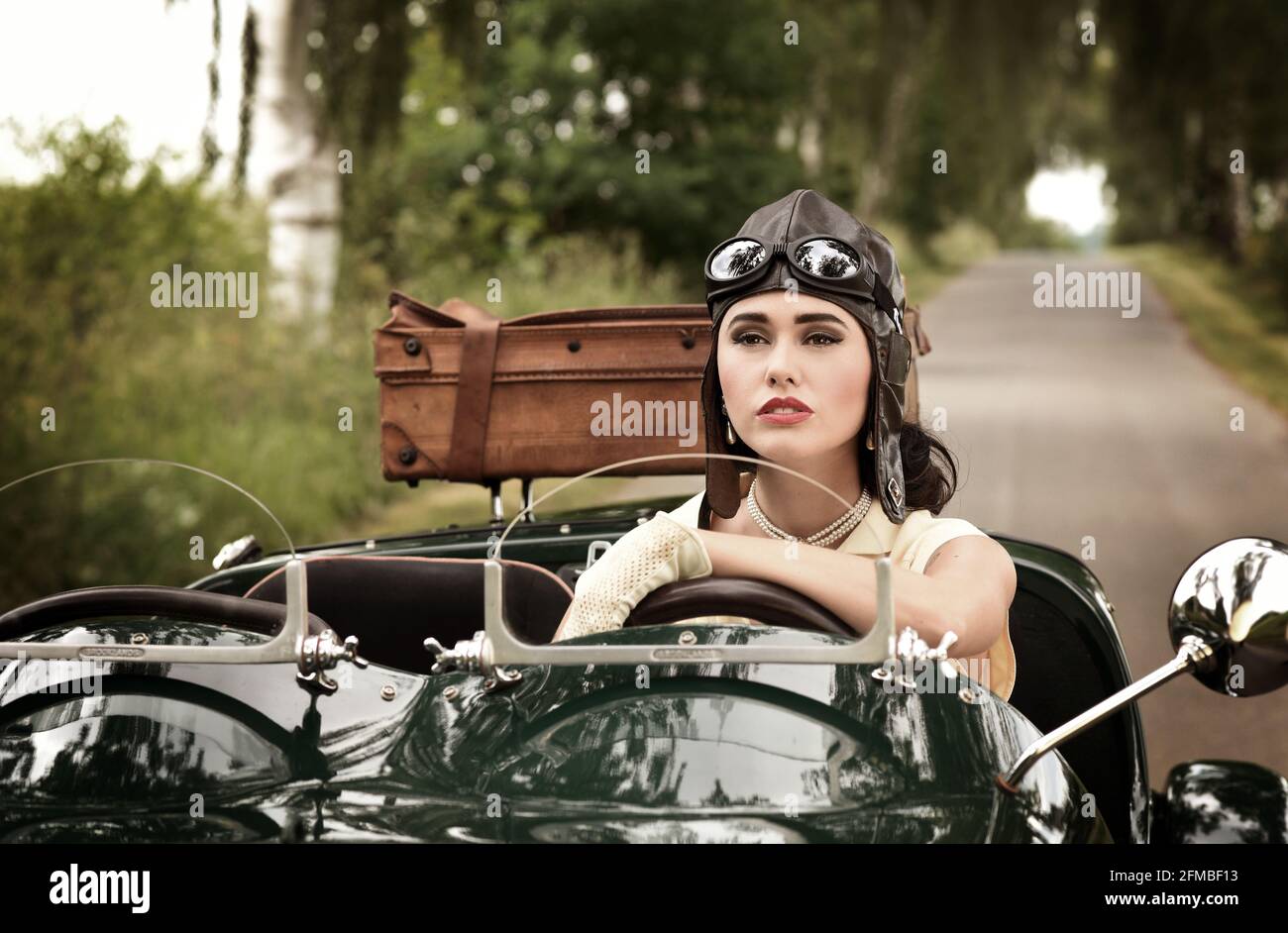 Giovane donna in stile anni '40 con auto d'epoca in British Racing Verde Foto Stock