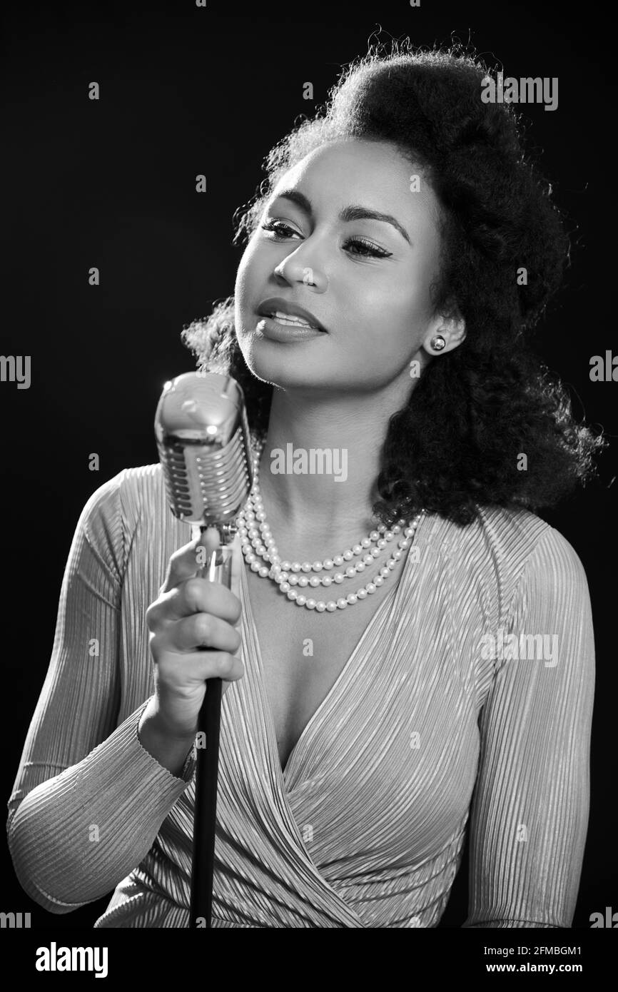 Cantante in stile anni '50 dalla pelle scura con microfono Foto Stock