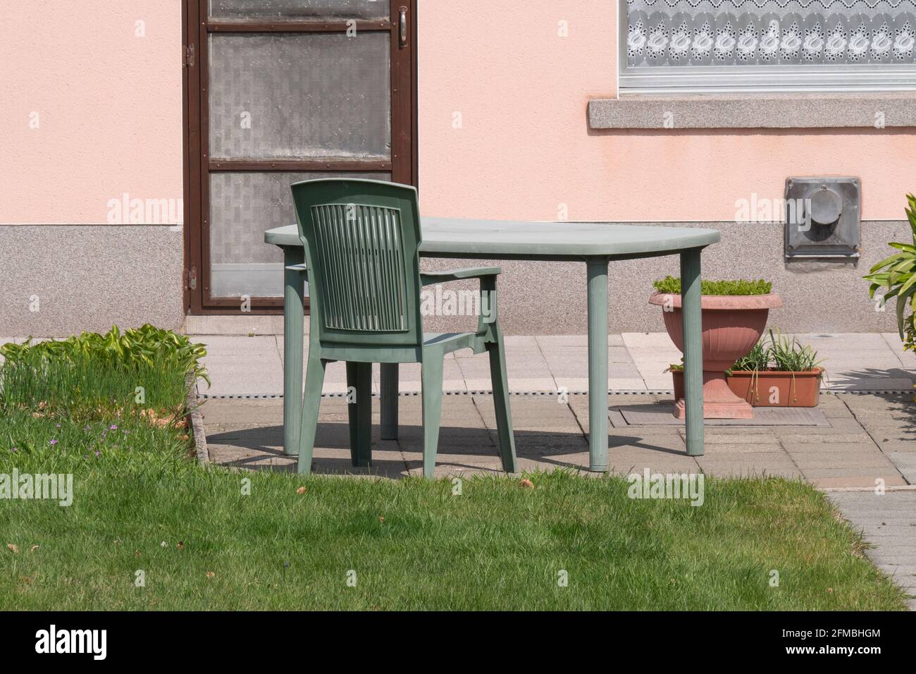 Tavolo da giardino in plastica verde e sedia da giardino scolorita dal sole Foto Stock