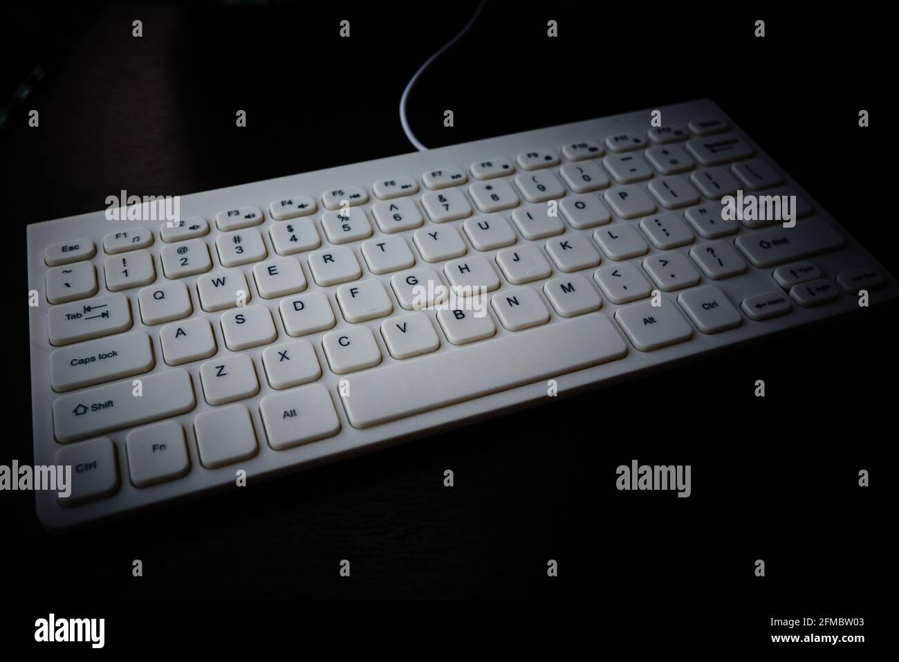 La tastiera bianca con layout in inglese si trova su un piano portapaziente nero Foto Stock
