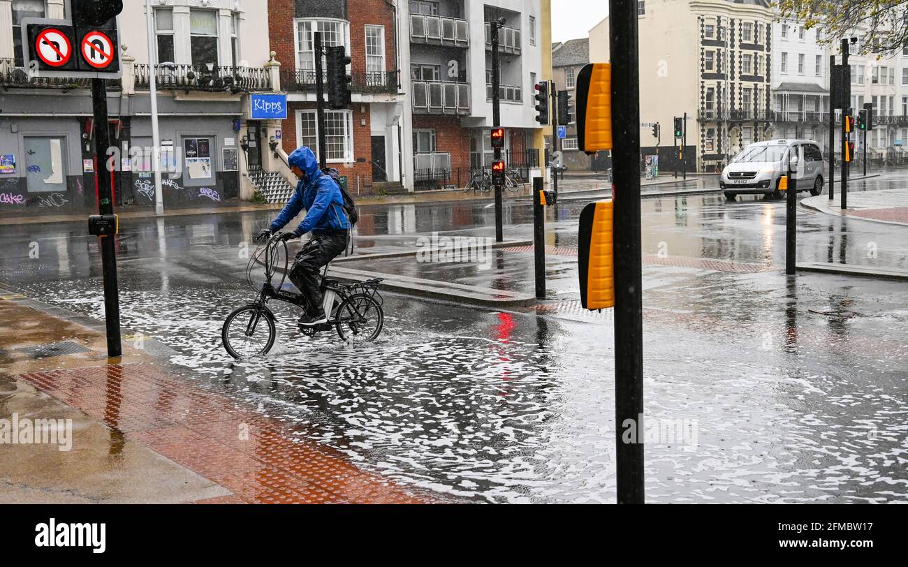 Brighton UK 8 maggio 2021 - UN ciclista attraversa le acque alluvionali sulle strade intorno alla zona dei Valley Gardens di Brighton, mentre la pioggia batte per la maggior parte della Gran Bretagna oggi, ma si prevede di riscaldarsi da domani nel Sud-Est : Credit Simon Dack / Alamy Live News Foto Stock