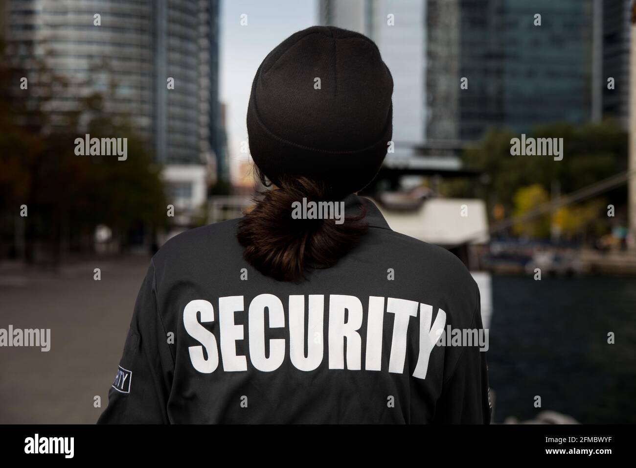 Guardia di sicurezza femminile pattugliando zona residenziale vicino porto ora giorno Foto Stock