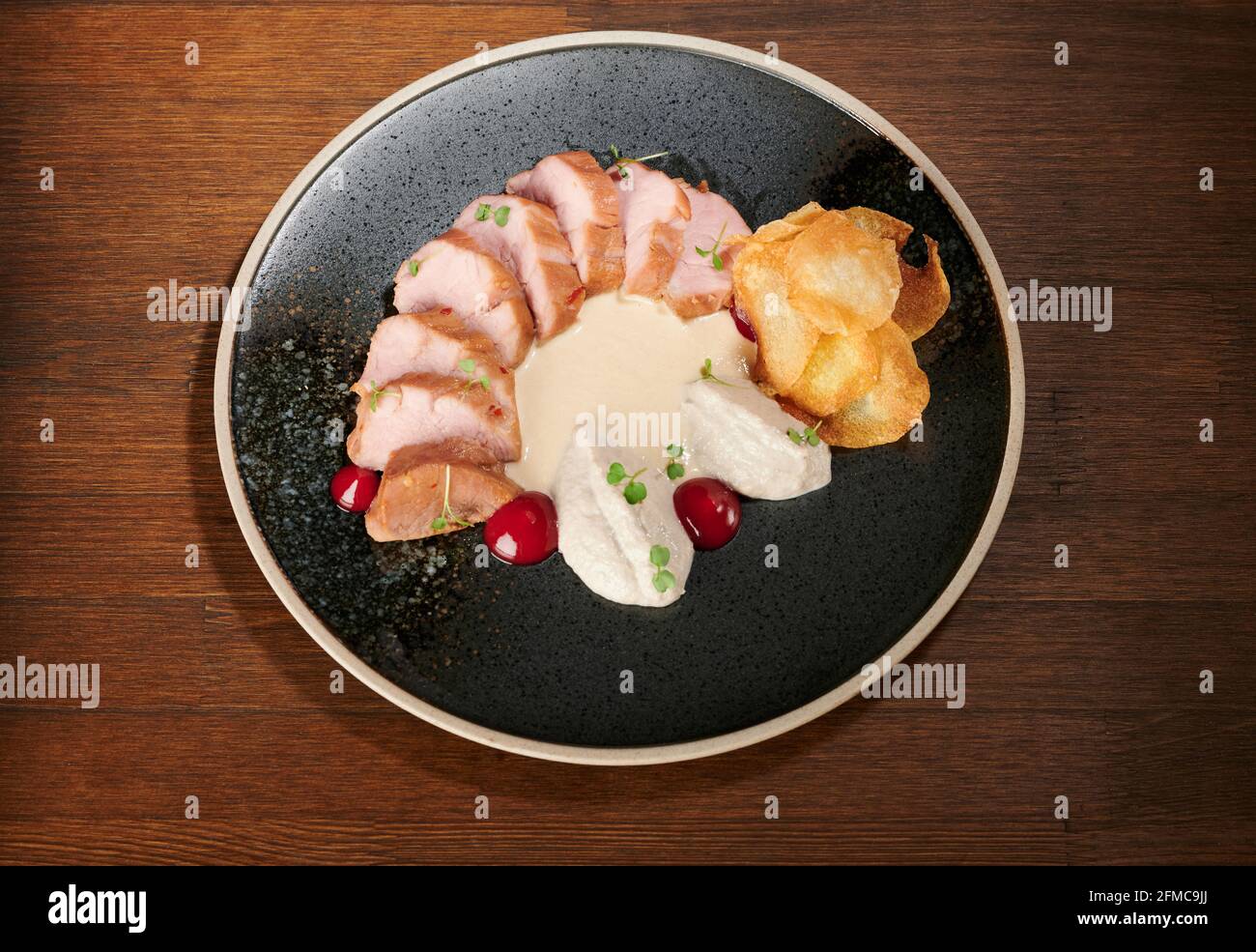 Succulenta carne di maiale affettata con salsa bianca su tavolo di legno Foto Stock