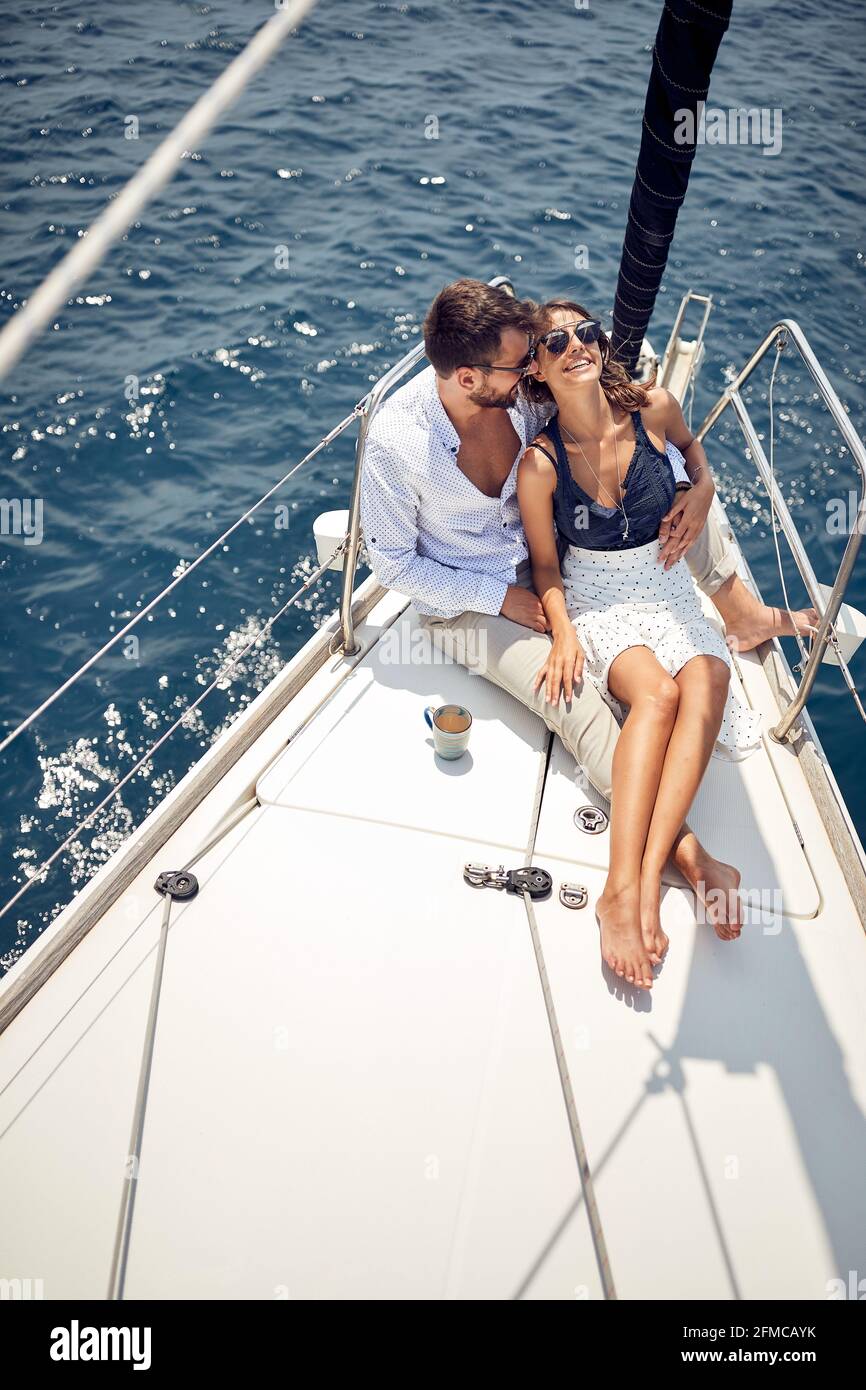 Una giovane coppia innamorata seduto sul prua dello yacht e godendo di momenti romantici mentre si viaggia in una bella giornata di sole sul mare. Estate, mare, vacanza Foto Stock