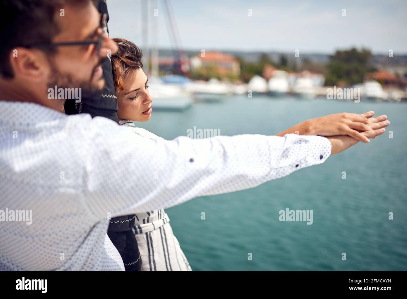 Una giovane coppia sta godendo momenti romantici sulla prua dello yacht insieme mentre cavalcano in una bella giornata estiva sul mare. Estate, mare, vacanze Foto Stock