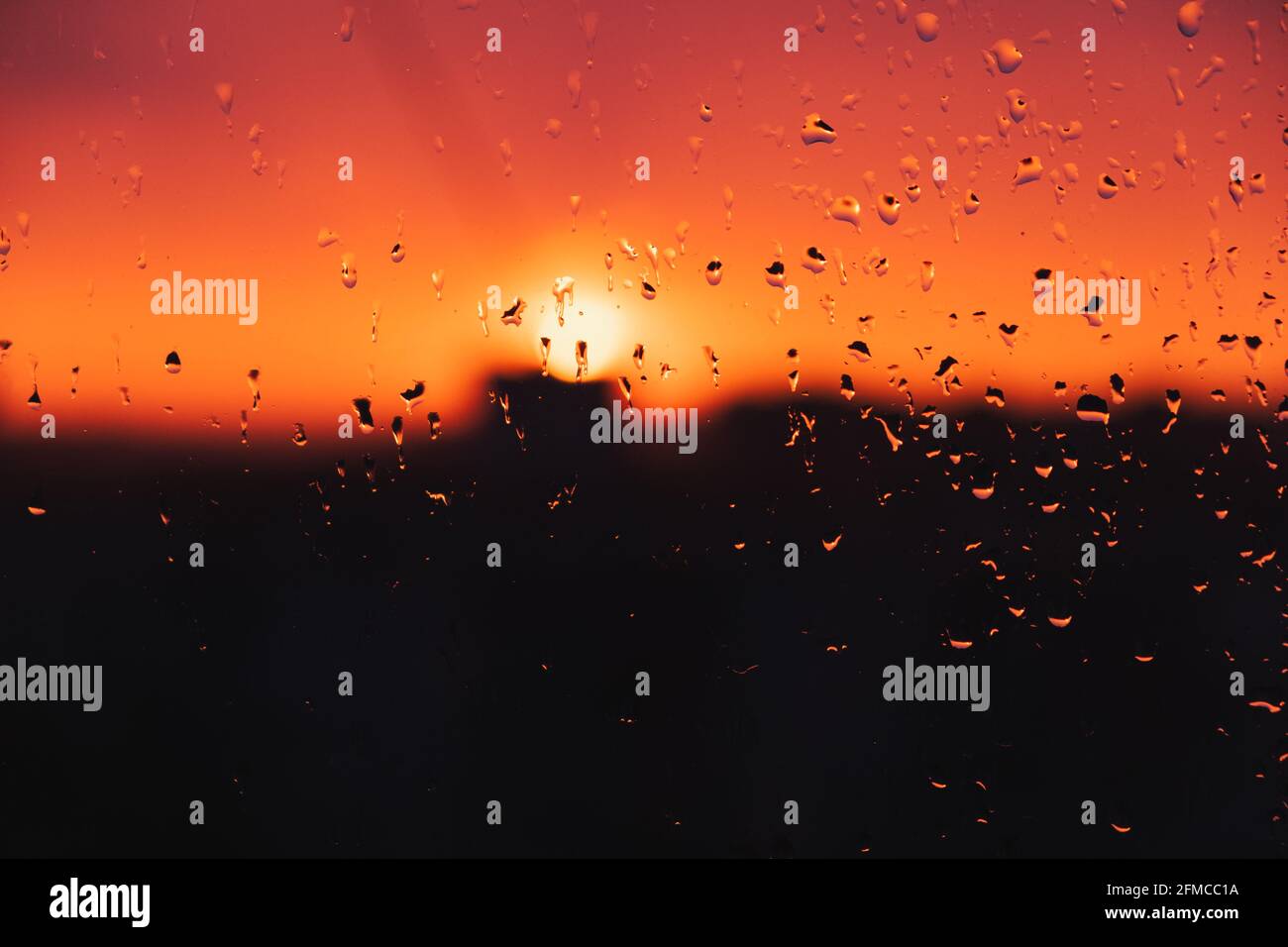 Gocce d'acqua piovana sulla finestra contro il cielo serale. Gocce di pioggia sul vetro, tramonto, immagine legata al tempo Foto Stock