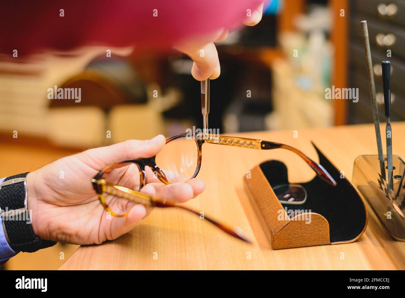 Closeup di mani optoetiste/optoetiste maschili che riparano gli occhiali Foto Stock