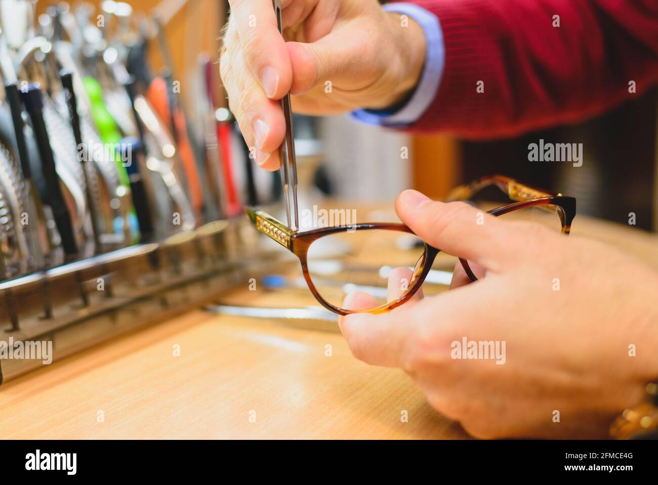 Closeup di optometristo maschile / mani di ottico riparazione occhiali Foto Stock
