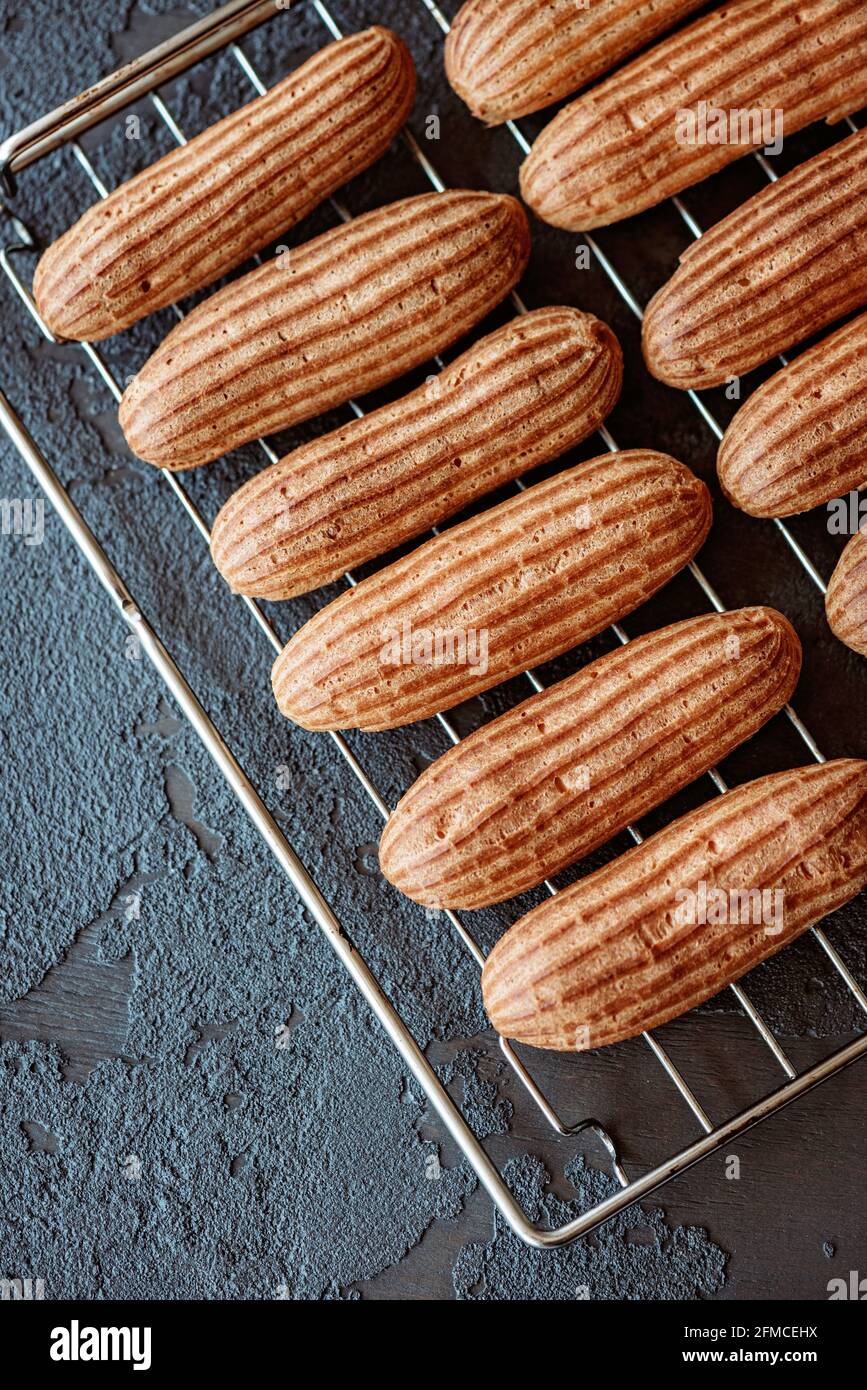 Dessert di pasticceria francese eclair. Le torte di crema aromatiche appena sfornate si raffreddano sulla griglia. Messa a fuoco selettiva morbida. Foto Stock