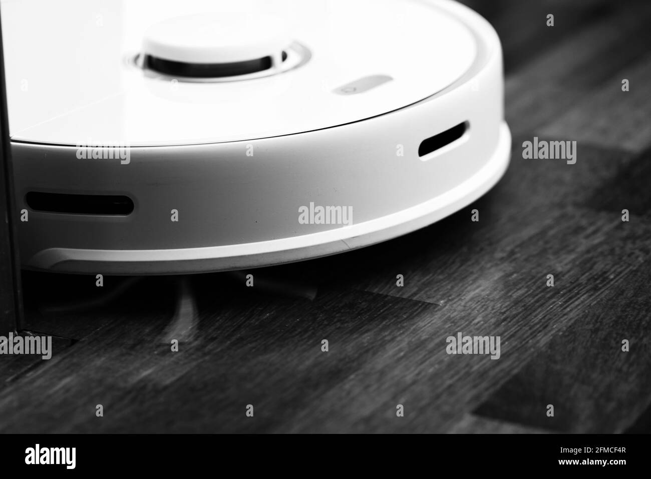 Aspirapolvere Smart Robot su pavimento in legno. L'aspirapolvere robot esegue la pulizia automatica dell'appartamento in un determinato momento. Casa intelligente. Foto Stock