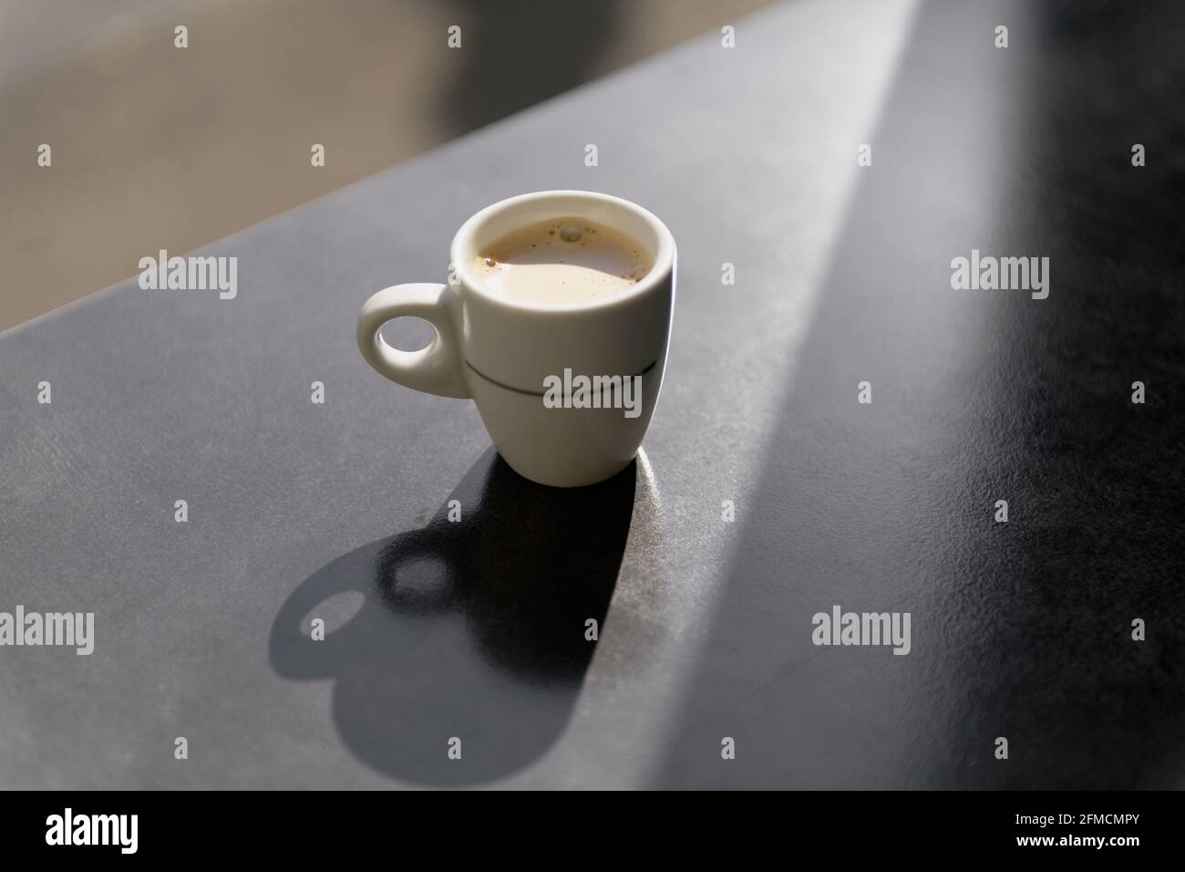 una tazza di caffè con ombre sul dorso grigio Foto Stock