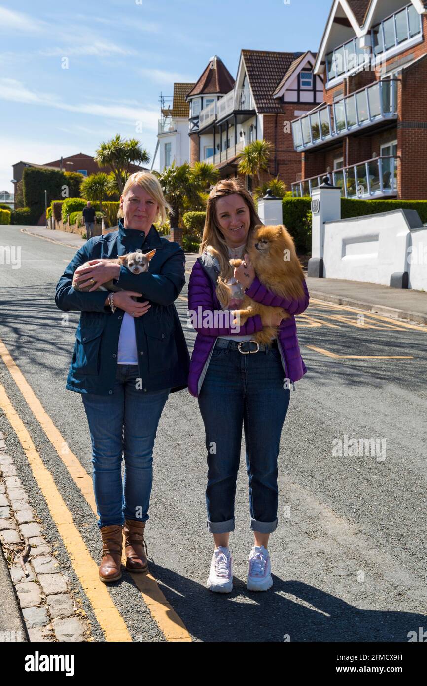 Due donne che tengono cani, una a Pomeranian e una a Chihuahua a Bournemouth, Dorset UK in una calda giornata di sole a maggio Foto Stock