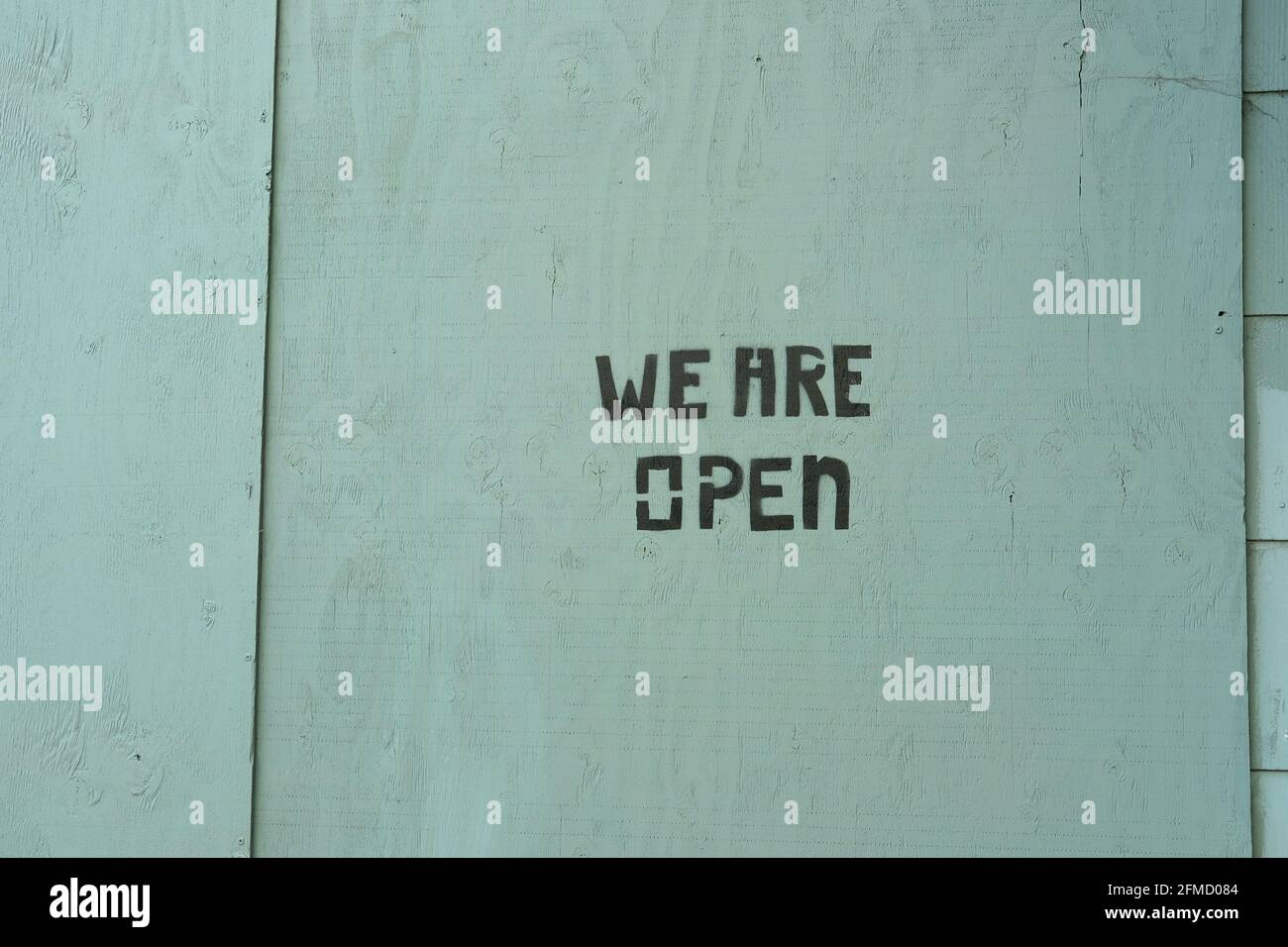 Siamo aperti stenciled su legno compensato che copre una finestra rotta; testo stencil su legno; business, ristorante riapertura dopo 2020 Covid pandemic shutdown. Foto Stock