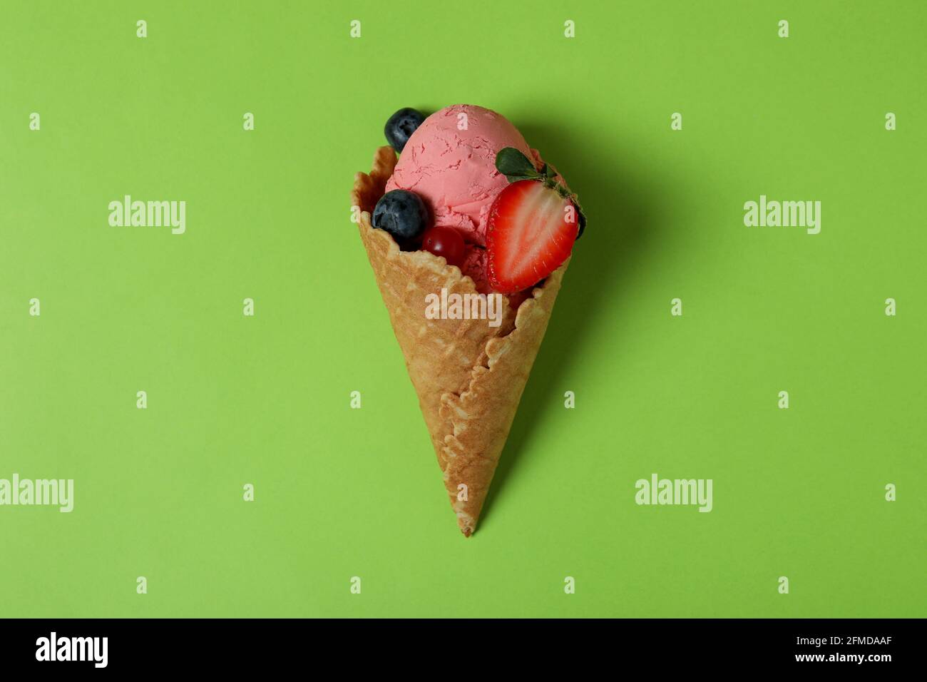 Cono di gelato alla frutta su sfondo verde Foto Stock
