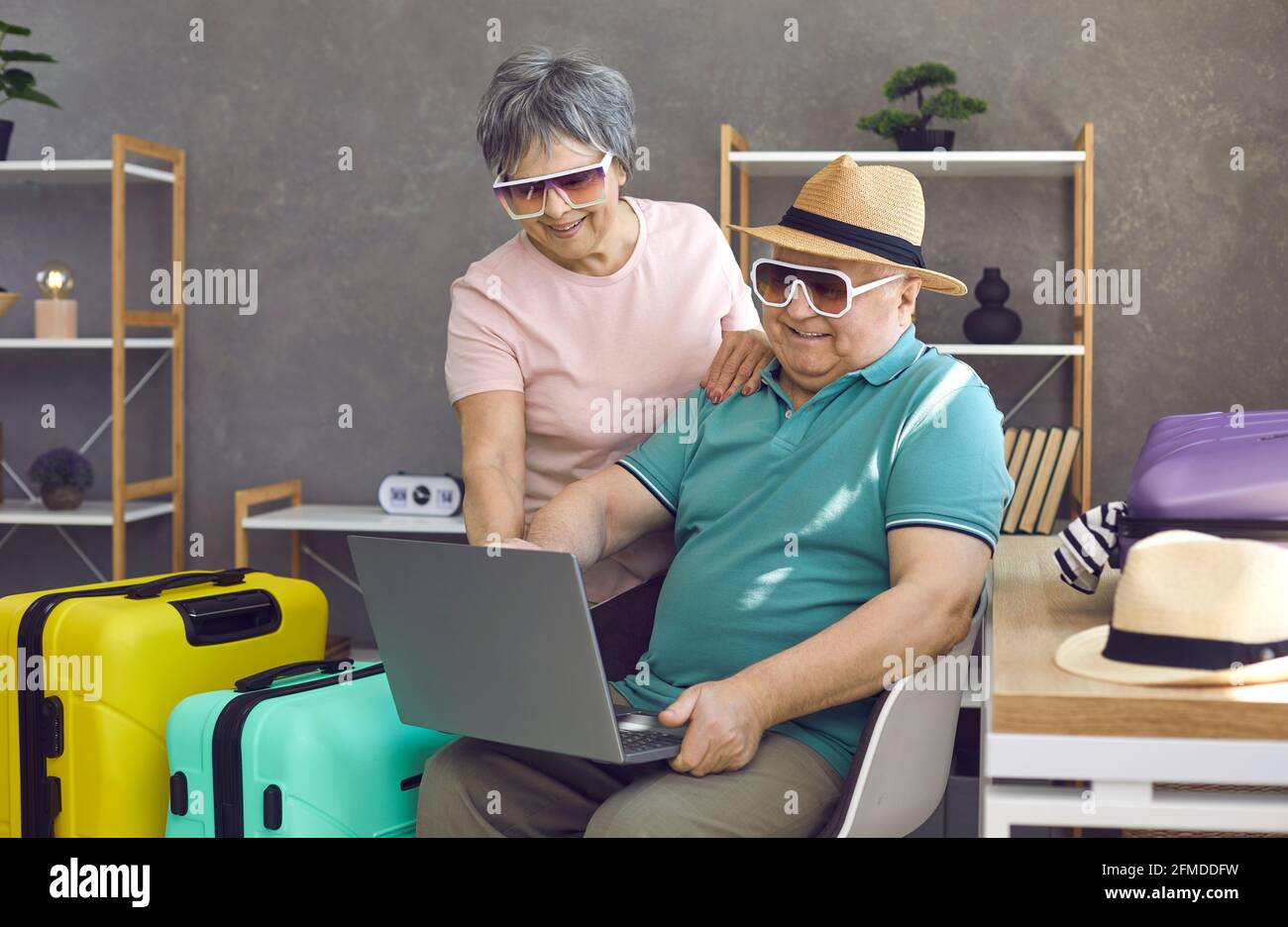 Coppia anziana divertente che usa il computer portatile per cercare e prenotare il tour vacanza Foto Stock