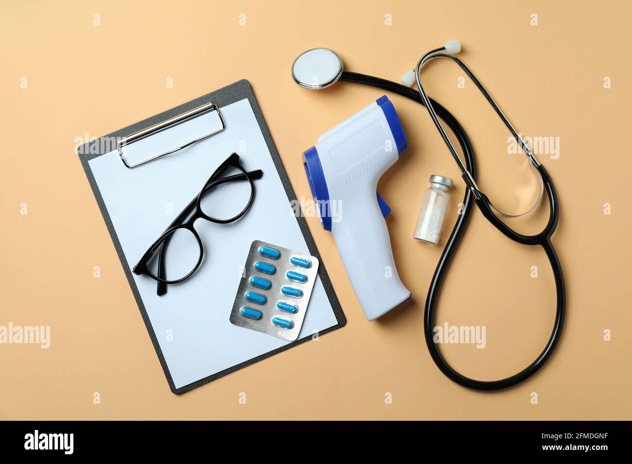 Strumenti medici e termometro a pistola su sfondo beige Foto Stock