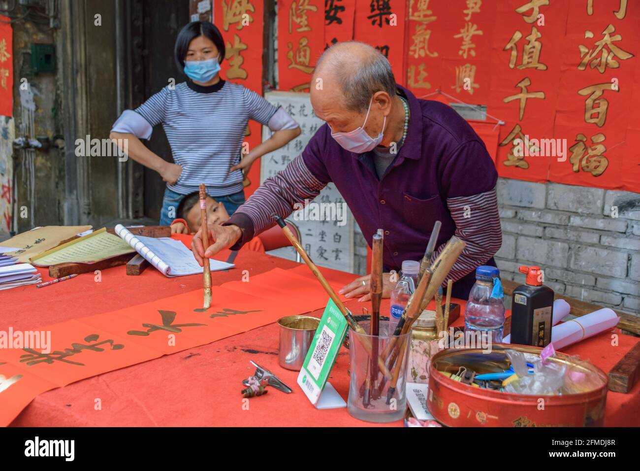 Foshan, provincia di Guangdong, Cina. 8 FEBBRAIO 2021. Un calligrafo sta scrivendo i couplets di festa della molla per la gente. È il cus più comune e importante Foto Stock