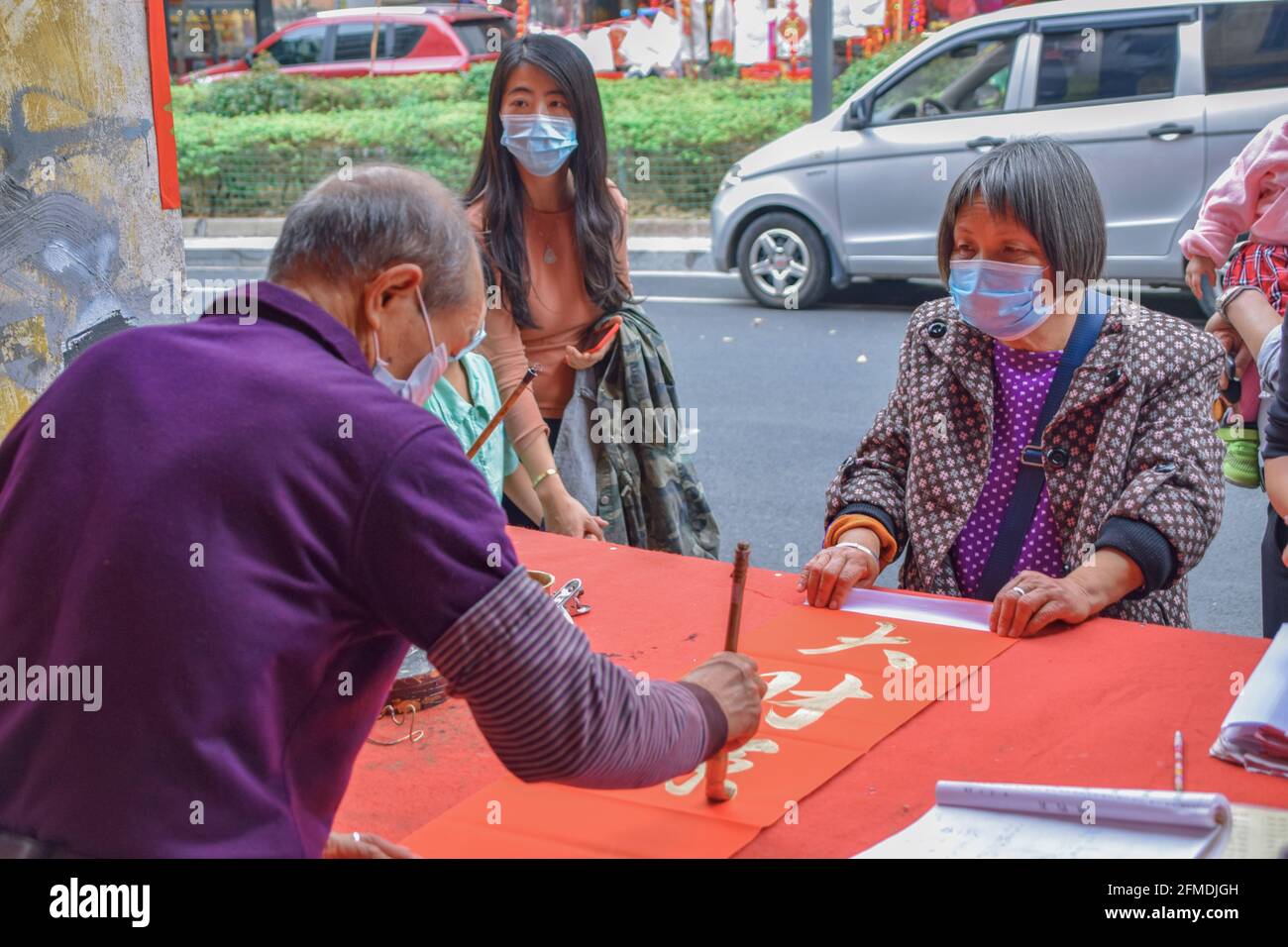 Foshan, provincia di Guangdong, Cina. 8 FEBBRAIO 2021. Un calligrafo sta scrivendo i couplets di festa della molla per la gente. È il cus più comune e importante Foto Stock