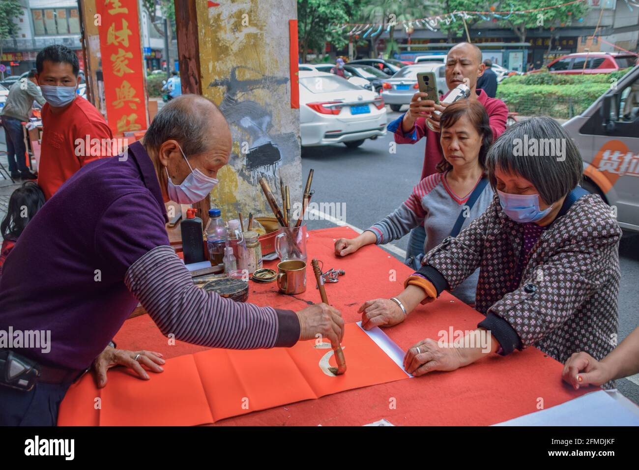 Foshan, provincia di Guangdong, Cina. 8 FEBBRAIO 2021. Un calligrafo sta scrivendo i couplets di festa della molla per la gente. È il cus più comune e importante Foto Stock