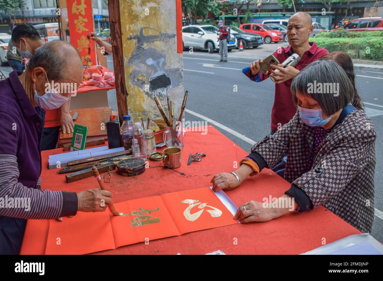 Foshan, provincia di Guangdong, Cina. 8 FEBBRAIO 2021. Un calligrafo sta scrivendo i couplets di festa della molla per la gente. È il cus più comune e importante Foto Stock
