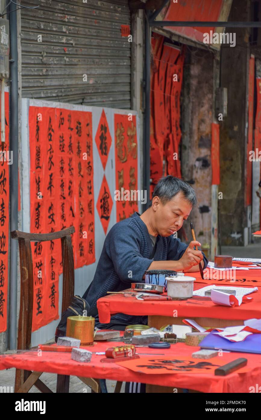 Foshan, provincia di Guangdong, Cina. 8 FEBBRAIO 2021. Un calligrafo sta scrivendo i couplets di festa della molla per la gente. È il cus più comune e importante Foto Stock