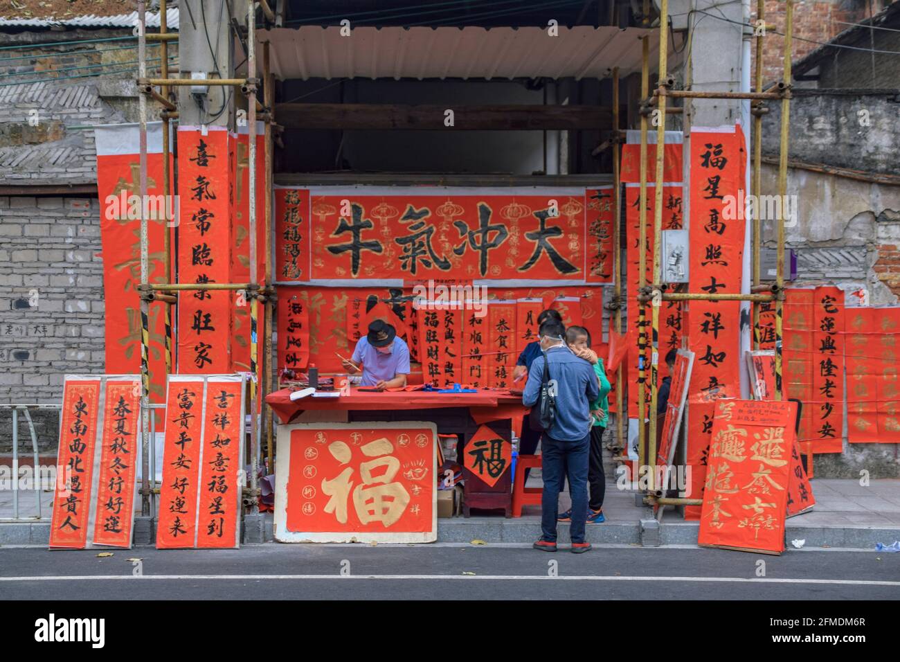 Foshan, provincia di Guangdong, Cina. 8 FEBBRAIO 2021. Un calligrafo sta scrivendo i couplets di festa della molla per la gente. È il cus più comune e importante Foto Stock