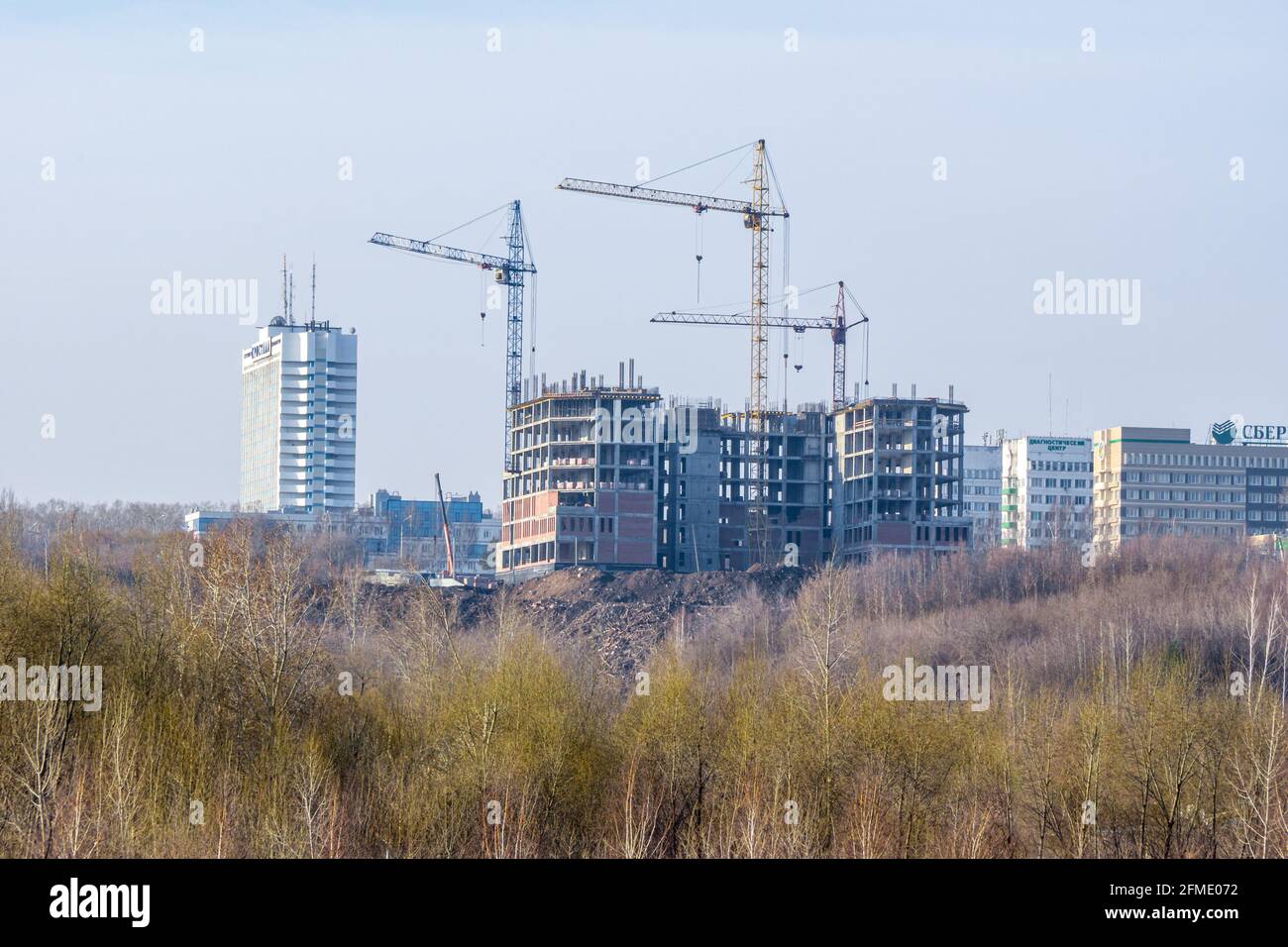 Kemerovo, Russia - 29 aprile 2021. Costruzione di un edificio a telaio con gru a torre. Nuova costruzione del servizio fiscale in città. SBER - iscrizione incompleta Foto Stock