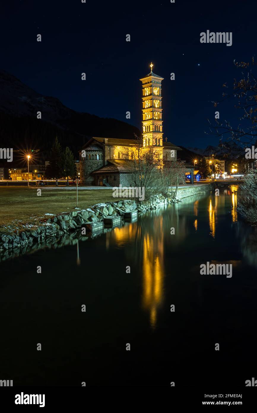 St. Moritz, Svizzera - 26 novembre 2020: Chiesa cattolica illuminata di St. Mauritius nell'ora blu e il suo riflesso nel lago Foto Stock