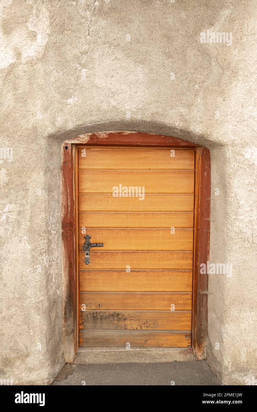 Mustair, Svizzera - 8 settembre 2020: La porta bassa in legno di una vecchia casa a Mustair Foto Stock