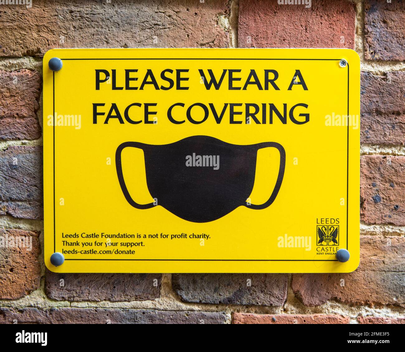 Kent, UK - 1 maggio 2021: Primo piano di un cartello che chiede ai visitatori di indossare una copertura facciale durante la visita agli spazi interni del castello di Leeds a Kent, Regno Unito. Foto Stock