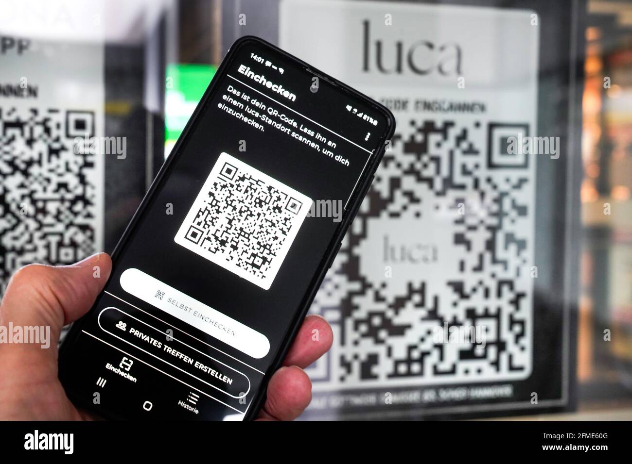 L'app Luca su smartphone esegue la scansione di un codice QR Luca  all'ingresso di un mercato alimentare di Hannover. È possibile effettuare  il check-in e il check-out con il telefono cellulare e