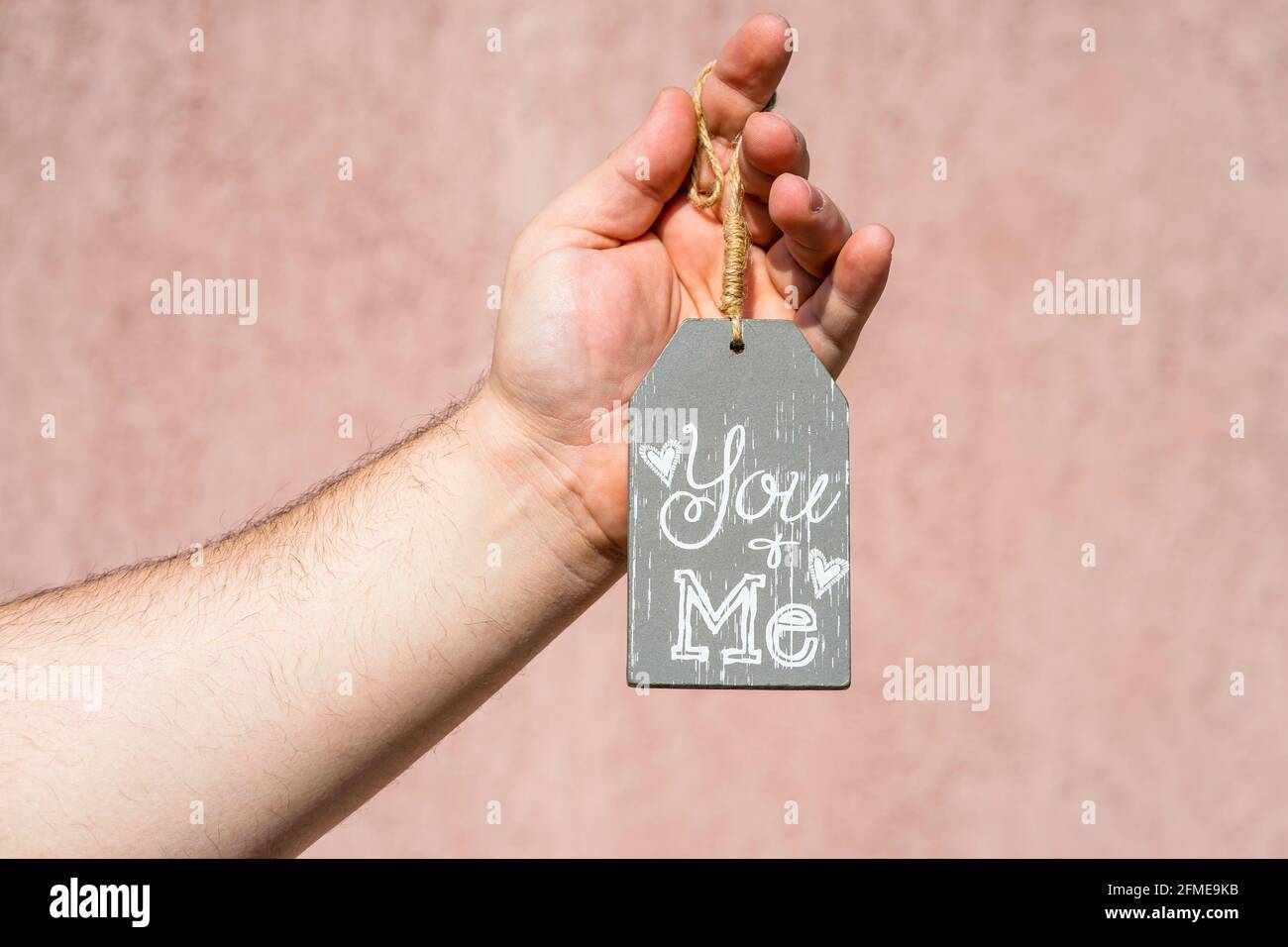 Mano maschile che tiene un'etichetta ornamentale con un messaggio di testo "Tu e me" Foto Stock