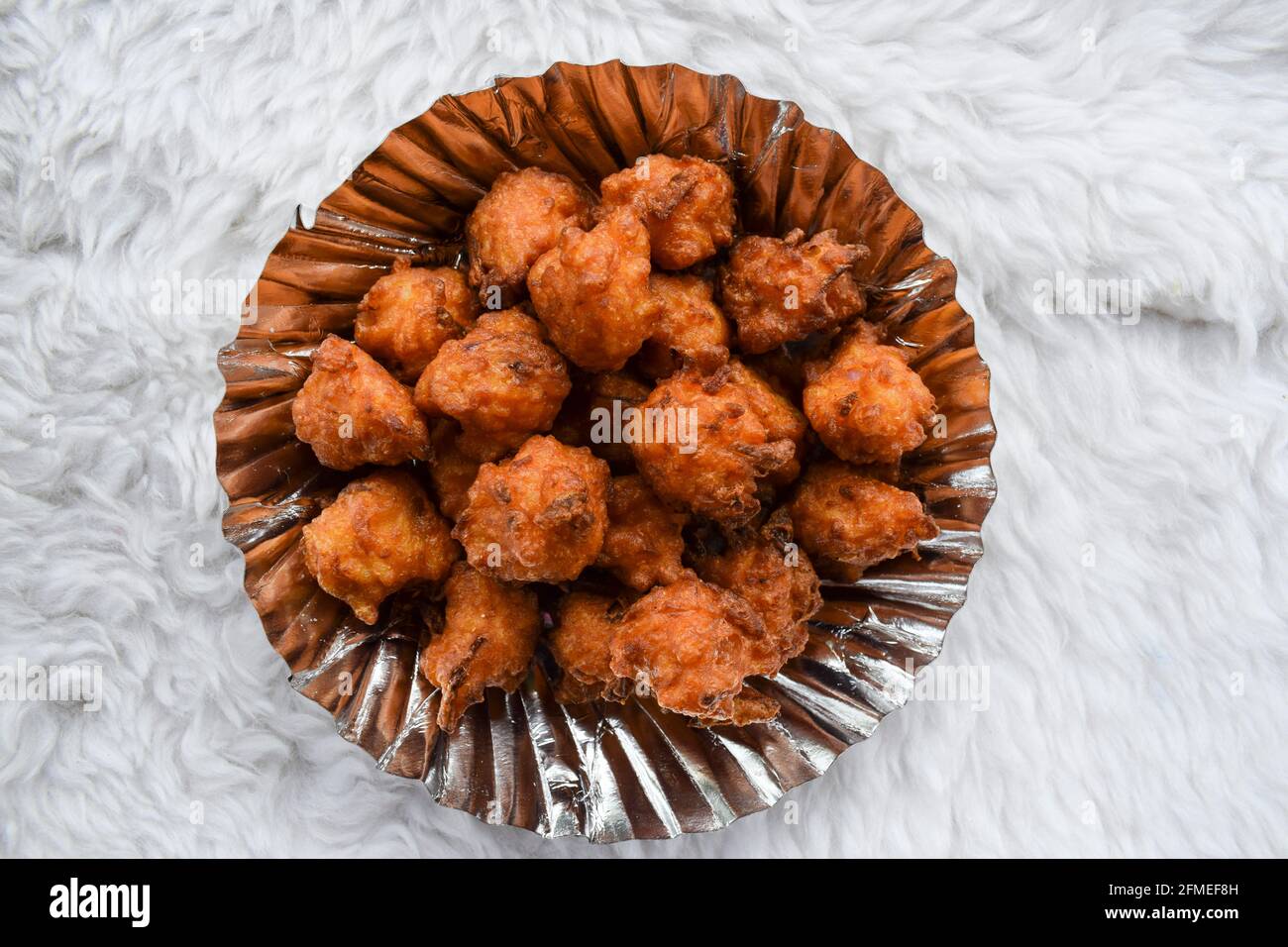 Il saporito bhajiya o pakoda di riso conosciuto anche come frittelle della sfera di riso è fatto da riso di sinistra, farina di grammo servita in piatto con tazza calda del masala t indiano Foto Stock