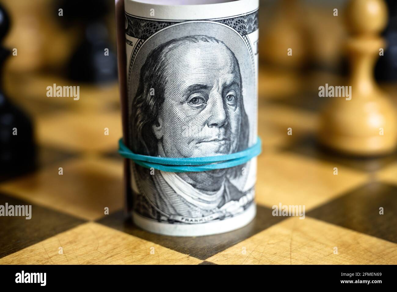 Le banconote in dollari rotolano con Franklin su scacchiera, contanti americani e scacchi. Conti di denaro americani e gioco di scacchi. Concetto di strategia aziendale, investimento, s Foto Stock