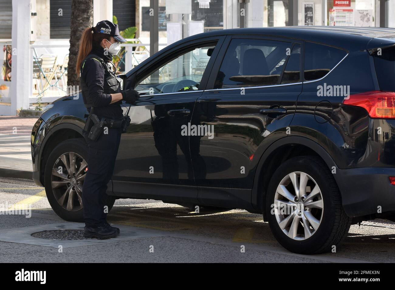 Un ufficiale della polizia locale di Vendrell con la sua arma di regolazione ferma un veicolo ad un checkpoint.This mattina striscioni di protesta sono comparsi di fronte al quartier generale della polizia locale di El Vendrell dove la polizia rivendica i loro diritti di lavoro. I membri della polizia locale di El Vendrell chiedono un cambiamento nella loro situazione occupazionale. Il Comitato del personale chiede che ai 22 agenti assunti temporaneamente venga dato un contratto fisso, in quanto tali agenti di polizia non dispongono delle armi necessarie o della formazione adeguata ed è pericoloso per loro e per il pubblico. Inoltre rivendicano lo stipendio arre Foto Stock