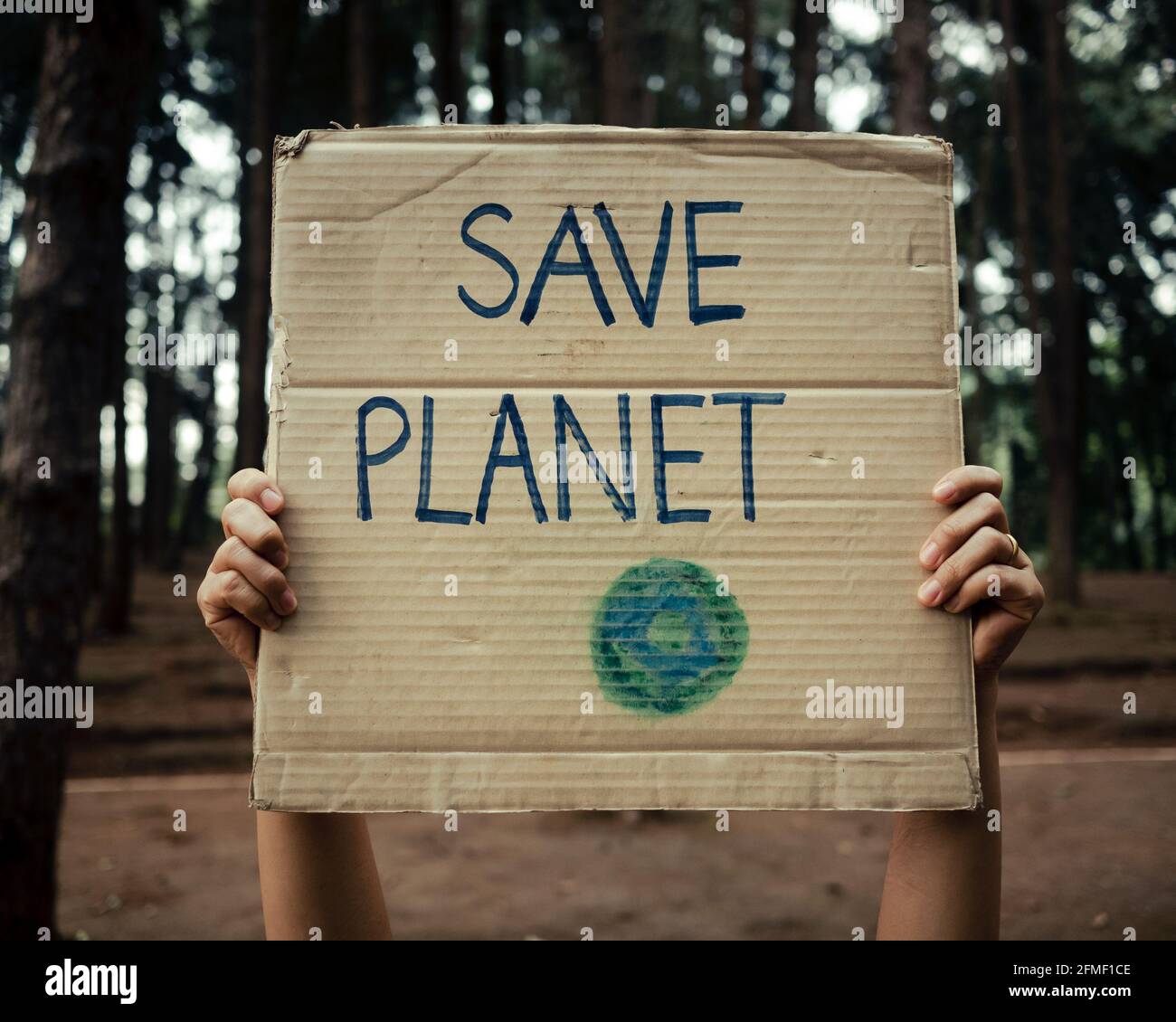 Striscioni con le mani che protestano per l'inquinamento e il riscaldamento globale nella foresta per salvare la terra del pianeta. Il concetto di Giornata Mondiale dell'ambiente. Foto Stock