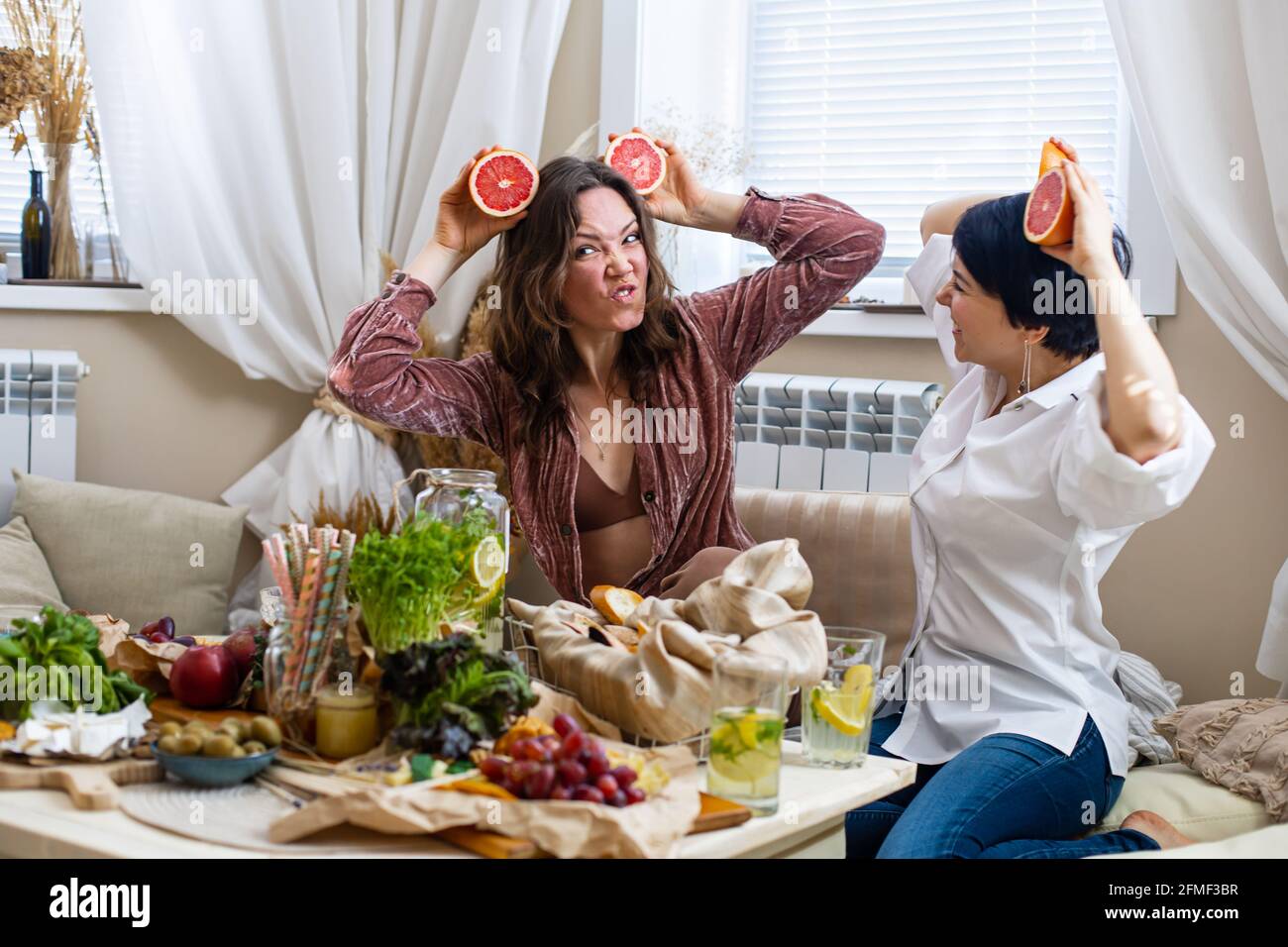 Felici le amiche che mostrano lingue che si posano con metà di pompelmo sugli occhi ridendo alla festa di gallina Foto Stock