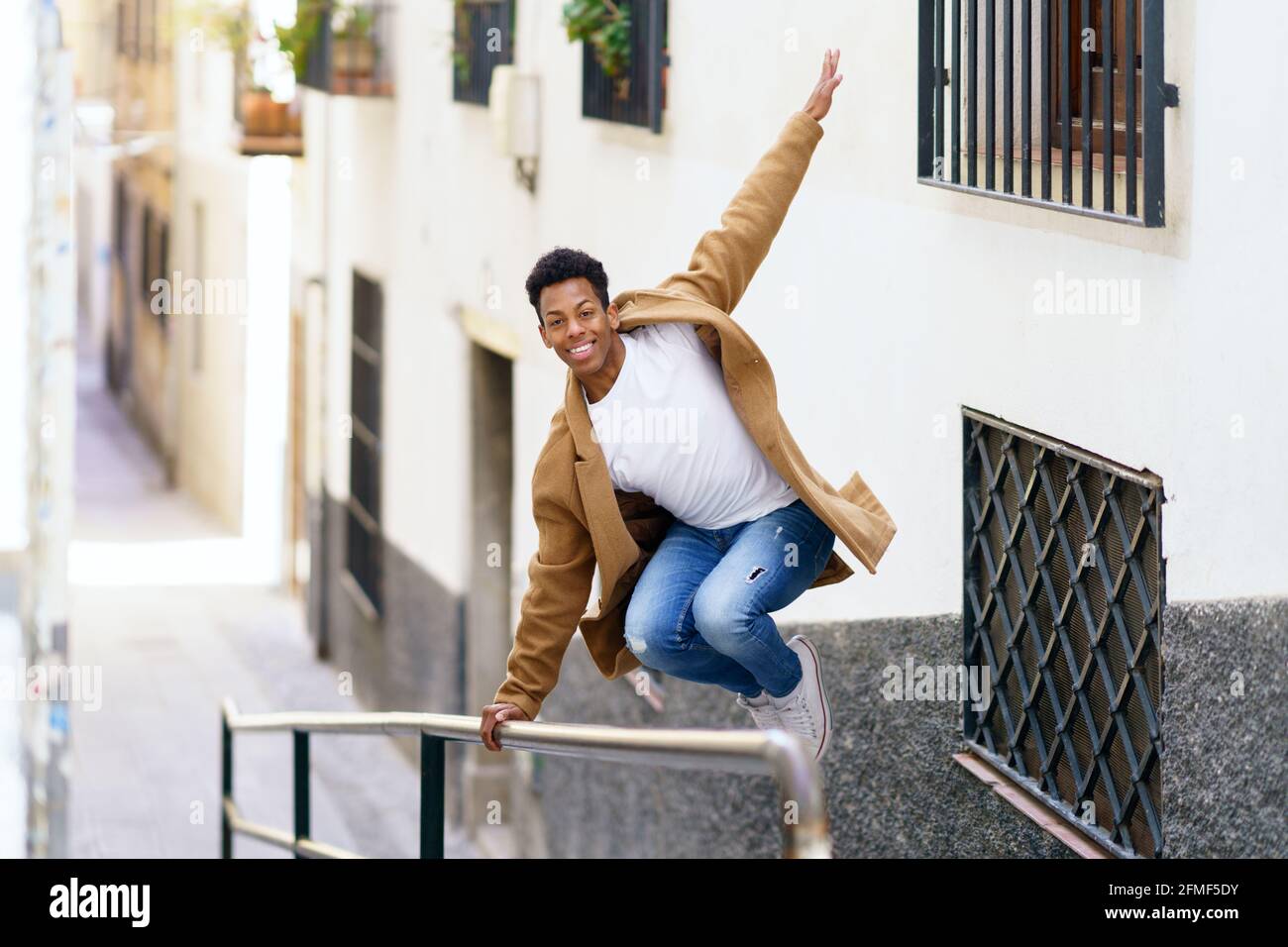 Uomo cubano che salta per gioia su un corrimano in strada. Foto Stock