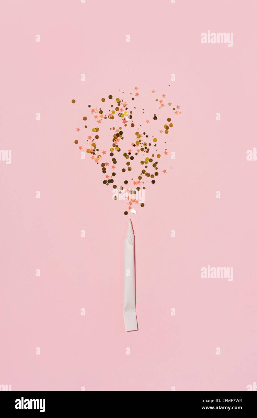 Esplosione di scintille da sigaretta di carta arrotolata hahd, su sfondo rosa pastello. Posa piatta. Foto Stock