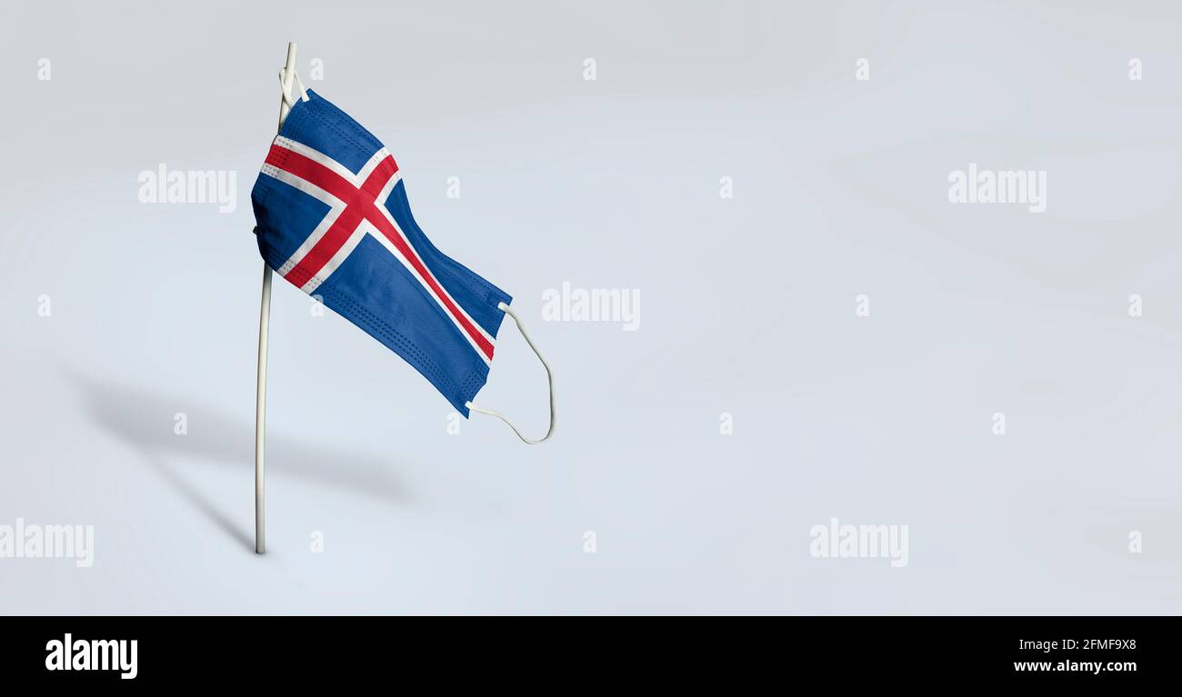 Maschera islandese su sfondo bianco. Bandiera ondulata dell'Islanda dipinta su maschera medica sul palo. Flag di attacco del virus. Concetto della bandiera della lotta contro Foto Stock