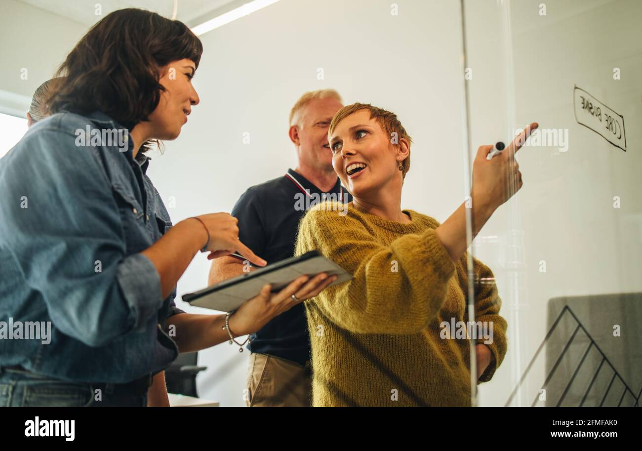Team creativo che discutono e mettono le idee sul vetro. dirigenti aziendali in piedi a parete di vetro e strategia di pianificazione. Foto Stock