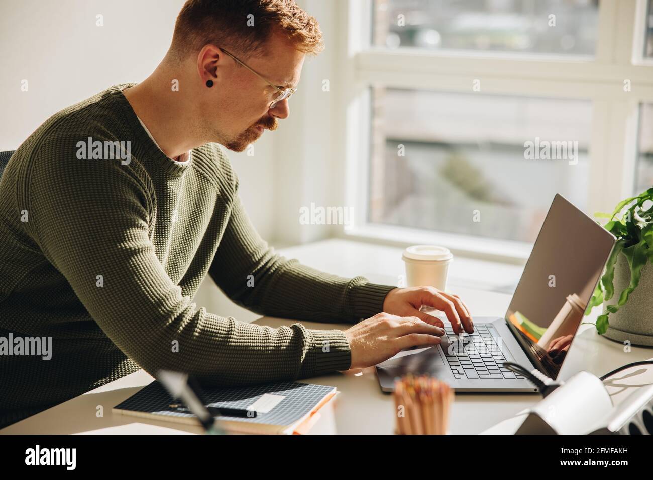 Dirigente maschile che lavora su un computer portatile. uomo d'affari seduto alla sua scrivania e legato al portatile. Foto Stock