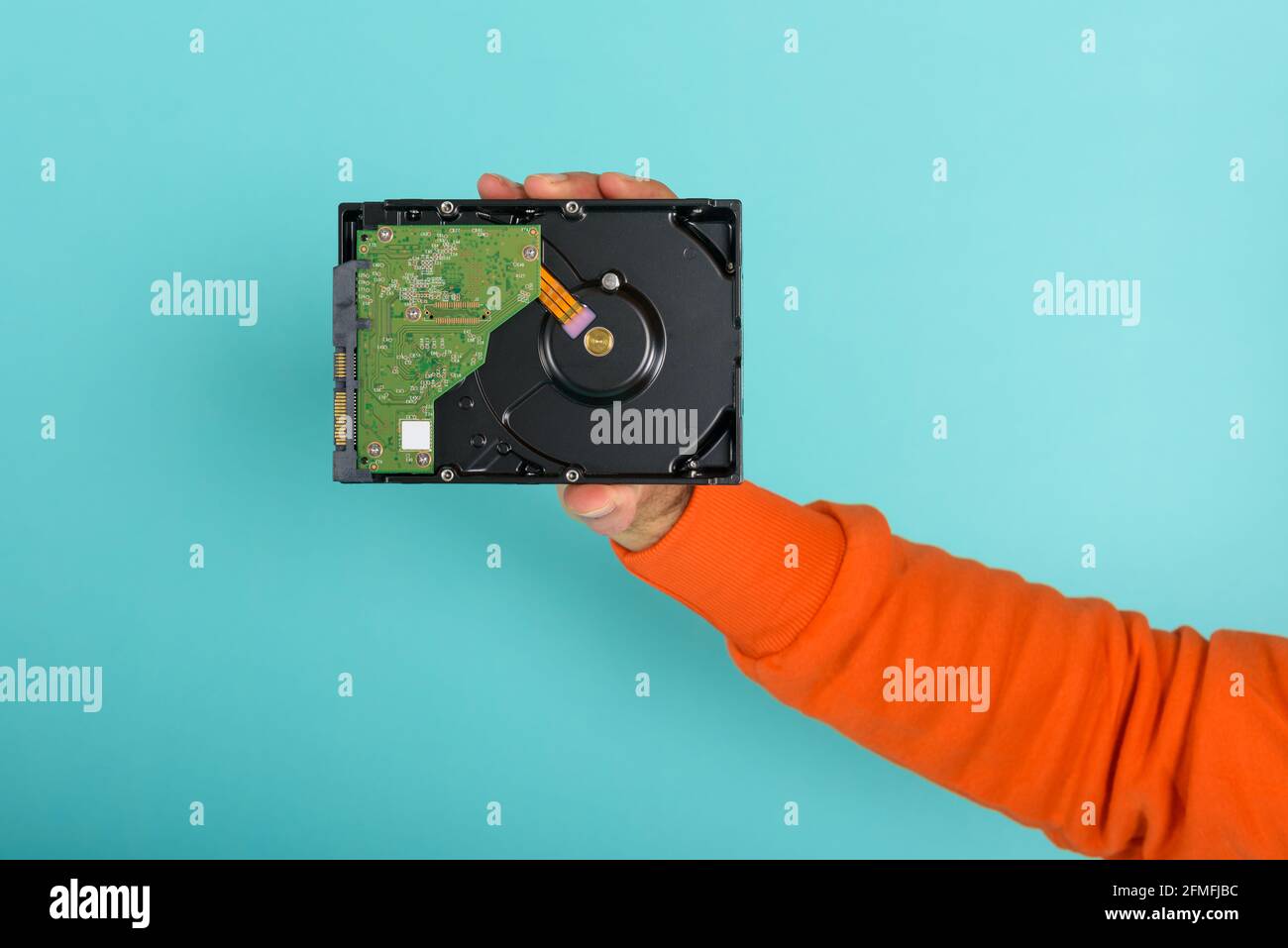 Man possiede un hard disk. Concetto di memoria e memoria. Sfondo ciano Foto Stock