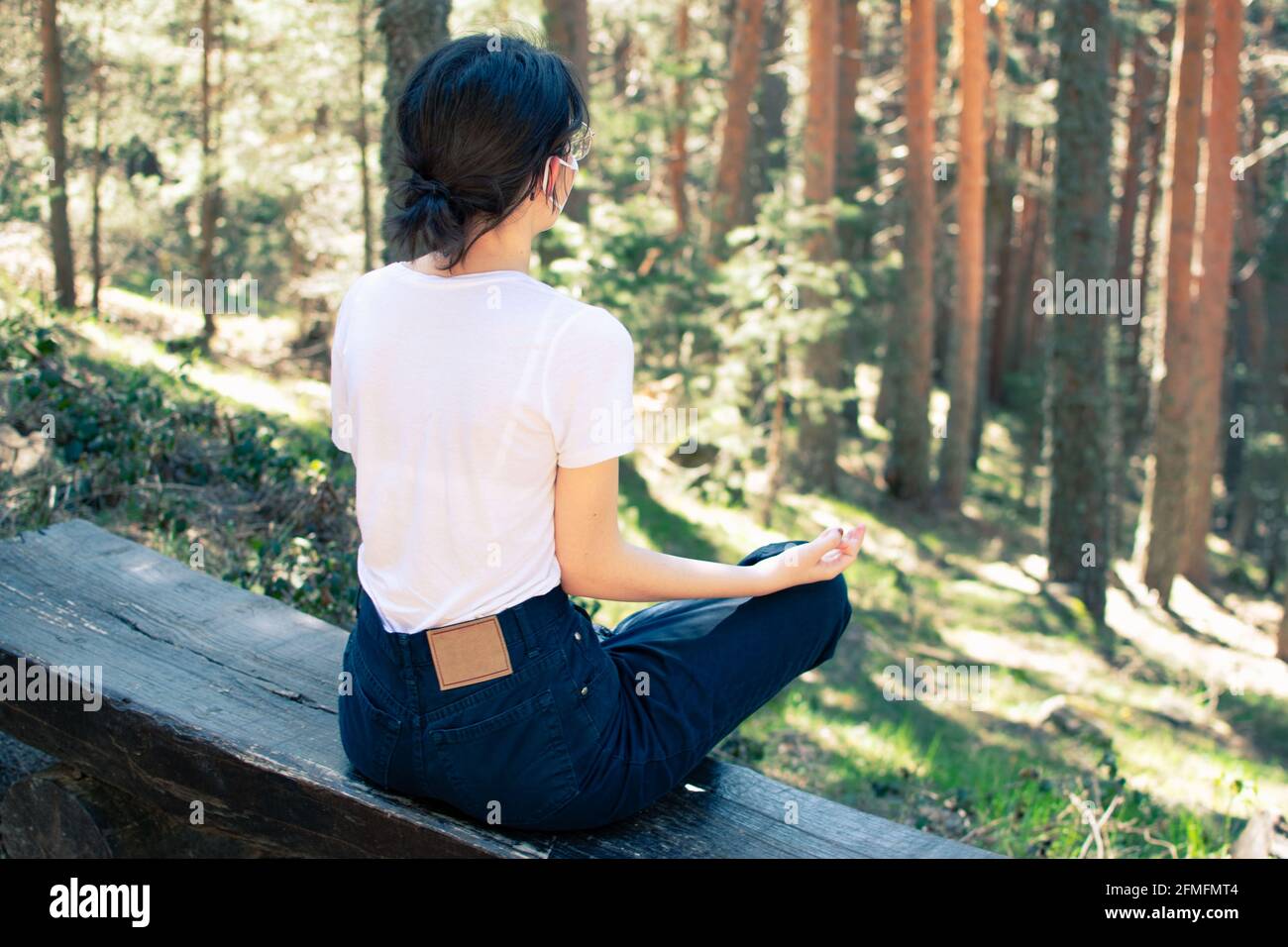 Donna con i capelli in su facendo yoga nella foresta. Orizzontale. Foto Stock