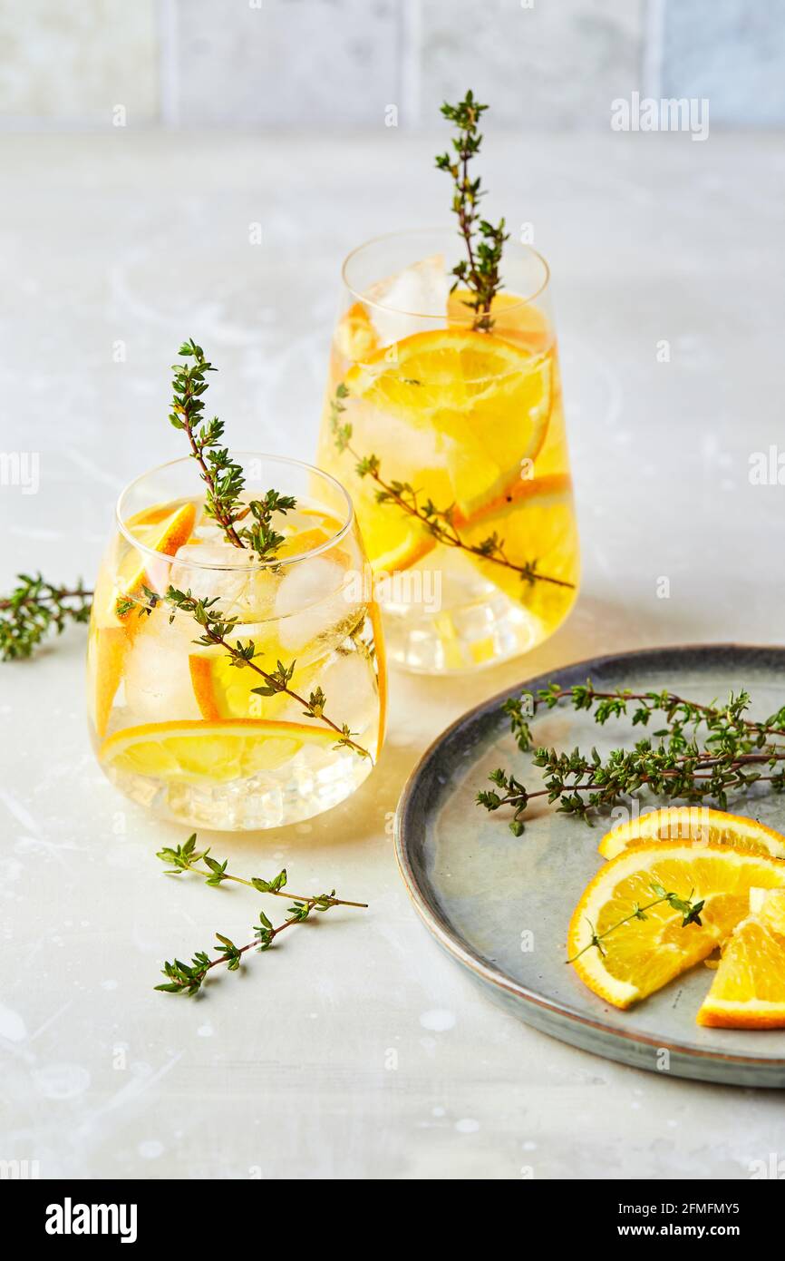 Cocktail rinfrescante con ghiaccio, arancia e timo. Rinfrescanti cocktail o mocktail alcolici o analcolici in casa, oppure infusi Detox aromatizzati Foto Stock