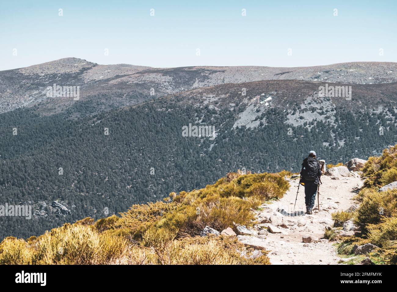 Escursionista sulla sua strada per la cima di una montagna con un grande paesaggio sulla sua sinistra e copia spazio. Foto Stock